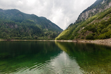 Naklejka na ściany i meble alpine high mountain lake, coniferous woods are reflected in the water, Antrona valley Campliccioli lake, Italy Piedmont