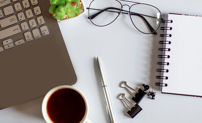 Office supplies, devices, coffee cup and glasses on white table