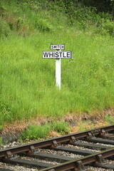 Whistle Railway Sign.  The view across railway track towards a sign requiring oncoming trains to blow their whistle.