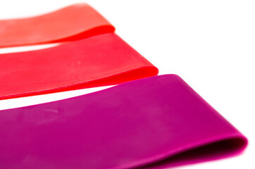 Elastic bands for fitness. Three elastic bands for fitness in close-up on a white background. Erasers lie on the table top and side view. A bunch of rezhinki, twisted into a roll. Elastic bands left 