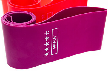 Elastic bands for fitness. Three elastic bands for fitness in close-up on a white background. Erasers lie on the table top and side view. A bunch of rezhinki, twisted into a roll. Elastic bands left 