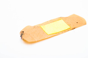 Used antibacterial patch on a white background in macro. Dirty patch, orange yellow top and side view