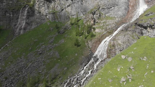 Aerial: drone flying over scenic high waterfall, mountain stream falling from tall rocky cliff on the italian Alps. Pis waterfall near Torino, Piedmont, Italy. Native d-log color profile