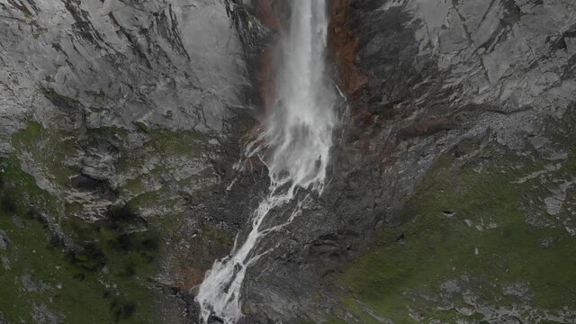 Aerial: drone flying over scenic high waterfall, mountain stream falling from tall rocky cliff on the italian Alps. Pis waterfall near Torino, Piedmont, Italy. Native d-log color profile
