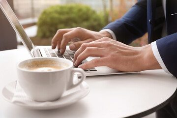Businessman working with laptop in outdoor cafe, closeup. Corporate blog