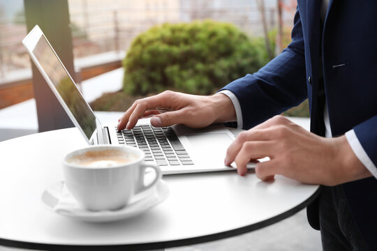 Businessman working with laptop in outdoor cafe, closeup. Corporate blog