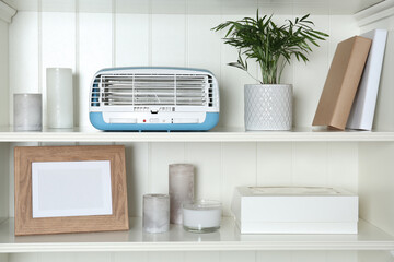 Modern air purifier and different items on white wooden shelves