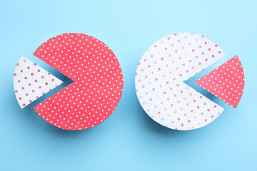Paper circles with exchanged segments on light blue background, flat lay. Pareto principle concept