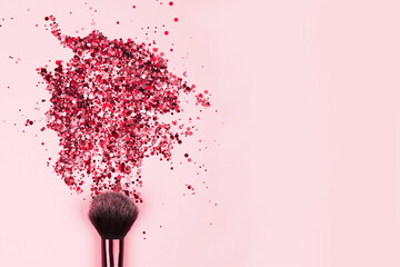 Closeup of professional cosmetics makeup brush with explosion of shiny pink colorful sparkles on bright pink background with copyspace for your text. Creative modern make-up concept