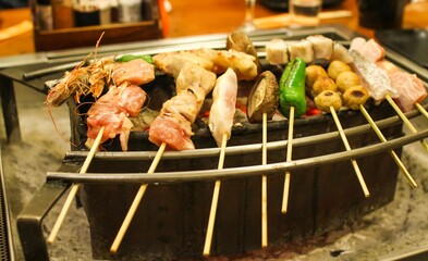 Japanese food, Kushiyaki, meat, fish and vegetables being grilled on a special grill place