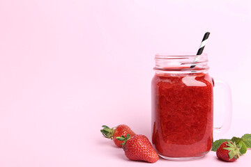 Tasty strawberry smoothie in mason jar on pink background. Space for text