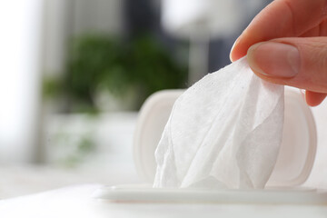 Woman taking wet wipe from pack on blurred background, closeup