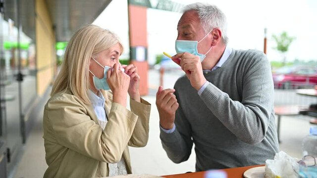 Mature man feeding a french fry to his wife during coronavirus times