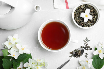 Flat lay composition with tea and fresh jasmine flowers on light grey marble table