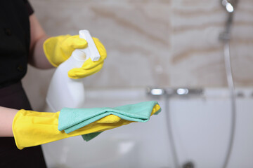 Cleaning service in an expensive hotel or at home. A woman in a uniform and rubber gloves.Cleanliness and hygiene in the bathroom.Unrecognizable photo. Only hand. Copy of the space.