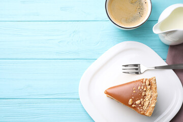 Piece of delicious cake with caramel served on light blue wooden table, flat lay. Space for text