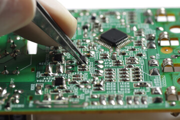Close up shoot of catching a small electronic component with a sharp pointed tweezers