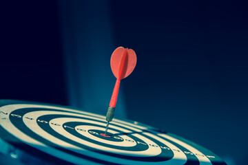 Bullseye or dart board has dart arrow throw hitting the center of a shooting target for business...