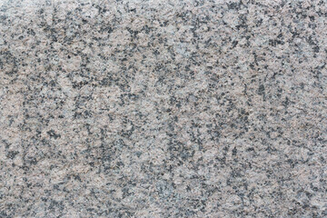 Granite texture. Natural gray granite with a grainy pattern. Stone background. Solid rough surface of rock. Durable construction and decoration material. Close-up.