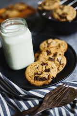Chocolate chips cookie and milk on a wooden plate.