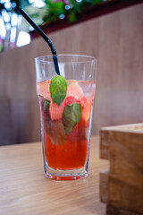 summer refreshing drink with ice and grapefruit and strawberries in a tall glass with a straw on the table. healthy lemonade.