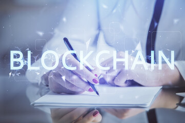 Cryptocurrency hologram over woman's hands writing background. Concept of blockchain. Double...