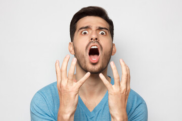 Why?! Young man asking about wrong decision, gesturing with both hands, isolated on gray background