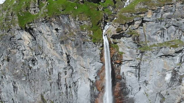 Aerial slow motion: drone flying over scenic high waterfall, mountain stream falling from tall rocky cliff on the italian Alps. Pis waterfall near Torino, Piedmont, Italy
