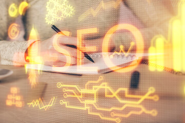Multi exposure of woman's hands making notes with SEO icon. Concept of Search engine optimization