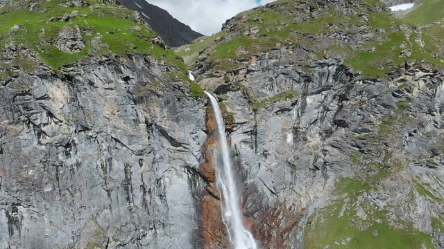 Aerial slow motion: drone flying over scenic high waterfall, mountain stream falling from tall rocky cliff on the italian Alps. Pis waterfall near Torino, Piedmont, Italy