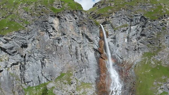 Aerial slow motion: drone flying over scenic high waterfall, mountain stream falling from tall rocky cliff on the italian Alps. Pis waterfall near Torino, Piedmont, Italy