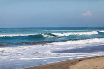 Fototapeta na wymiar KUTA, BALI, INDONESIA - february, 2020: Kuta beach in Bali. Many beginner surfers in the ocean take lesson. Surfing school.