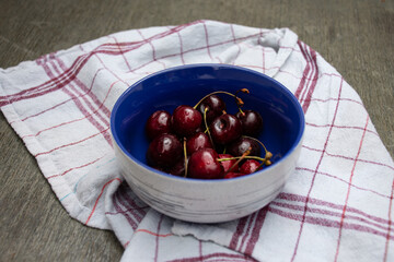 Blue fruit bowl filled with freshly picked red cherries