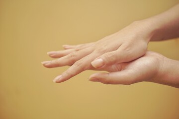 Close up of a hand using hand sanitizer with yellow backgorund.
