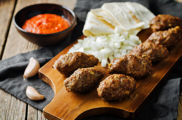 Minced meat sausage with onion, sour cream, pita and red bell pepper relish