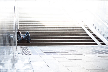 A lone homeless man sleeps on the steps of an underground passage. The concept of loneliness in a huge city. Space for text.