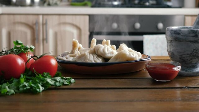 Khinkali, Georgian dumplings, traditional Georgian cuisine. Georgian dumplings Khinkali with meat, greens and tomato sauce on brown plate. Georgian national dish Khinkali.