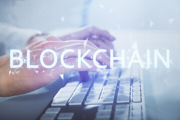 Crypto currency theme hologram with businessman working on computer on background. Concept of blockchain. Multi exposure.