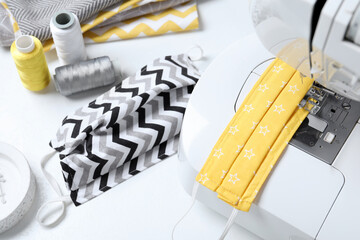 Sewing machine, homemade protective masks and threads on white table