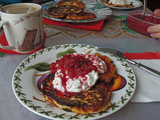 Breakfast of cottage cheese pancakes, cheesecakes with raspberries and sour cream.