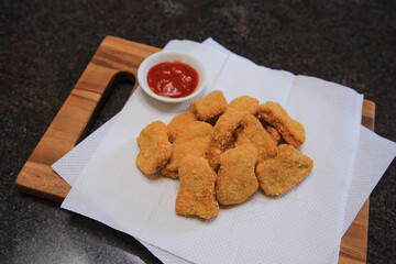 Serve chicken nuggets with vegetables and saur on a white plate