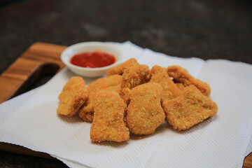 Serve chicken nuggets with vegetables and saur on a white plate
