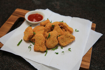 Serve chicken nuggets with vegetables and saur on a white plate