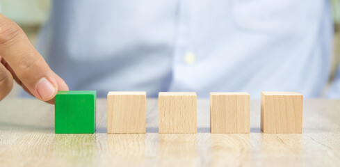 Close-up hand chooseing cube wooden block toy stacked without graphics for Business design concept and build activity for children play create and practices foundation stage.