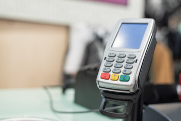 Payment pos terminal on a store counter background.