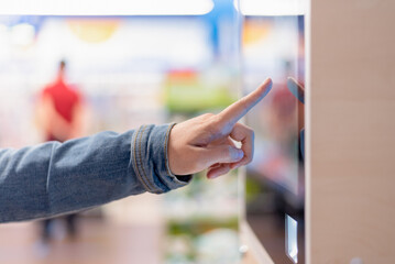 Woman is choosing a goods in an interactive information stand in the store.