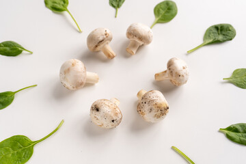 Fresh hampignons and spinach leaves on a white background. Top view. Healthy food for diet. 