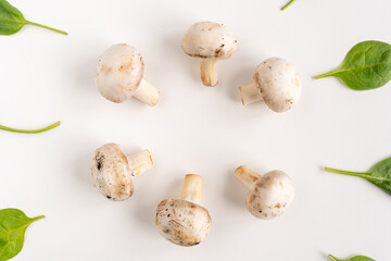 Fresh hampignons and spinach leaves on a white background. Top view. Healthy food for diet. Close-up