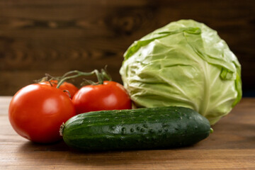 Fresh cabbage, tomatoes and cucumber on a brown wooden table. Vegetarian food. Healthy eating. 