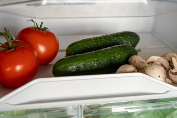 Fresh mushrooms, tomatoes and cucumbers in the refrigerator. Healthy diet nutrition. Vegetarian Vegetable. 